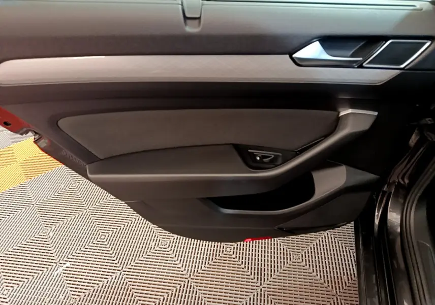 Panneau de porte intérieur côté gauche gris foncé de la Volkswagen Passat 2.0 TDI 2021 avec poignée intégrée et finition sobre.