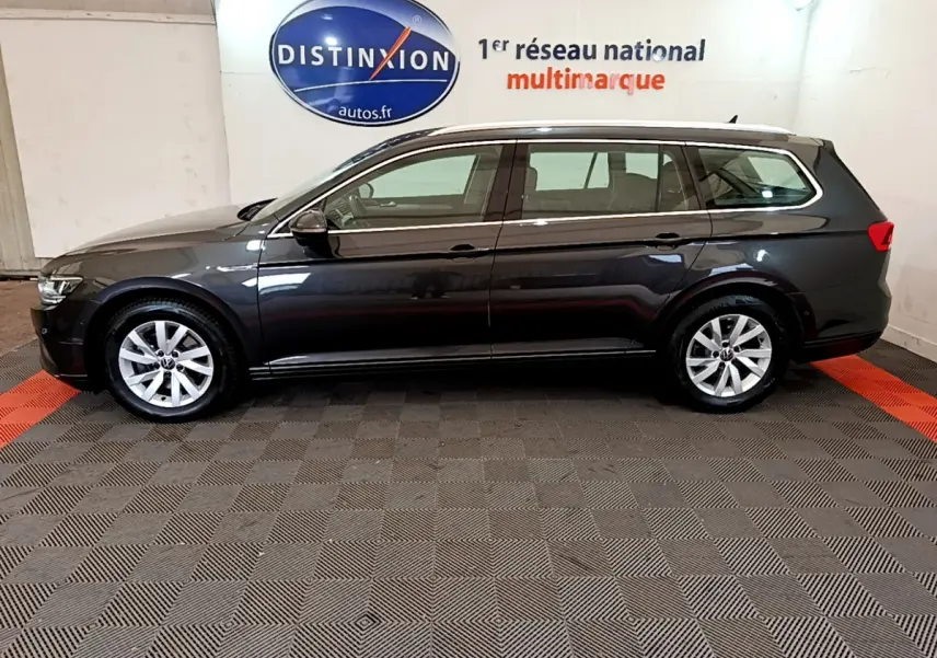 Profil côté gauche d'une Volkswagen Passat break gris foncé 2021, stationnée en intérieur sur sol damier.