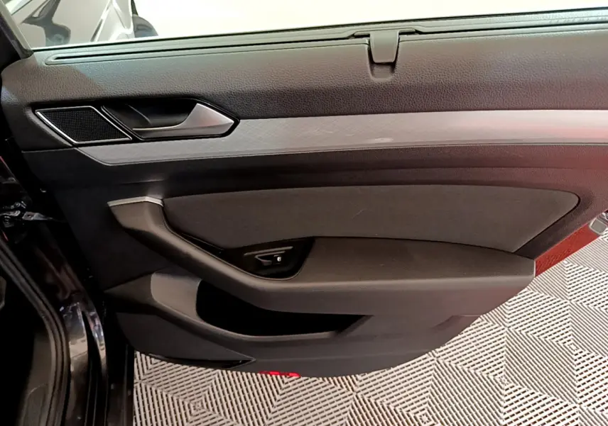 Gros plan sur la porte côté gauche gris foncé de la Volkswagen Passat 2021 avec poignée et commande de vitre intégrée.