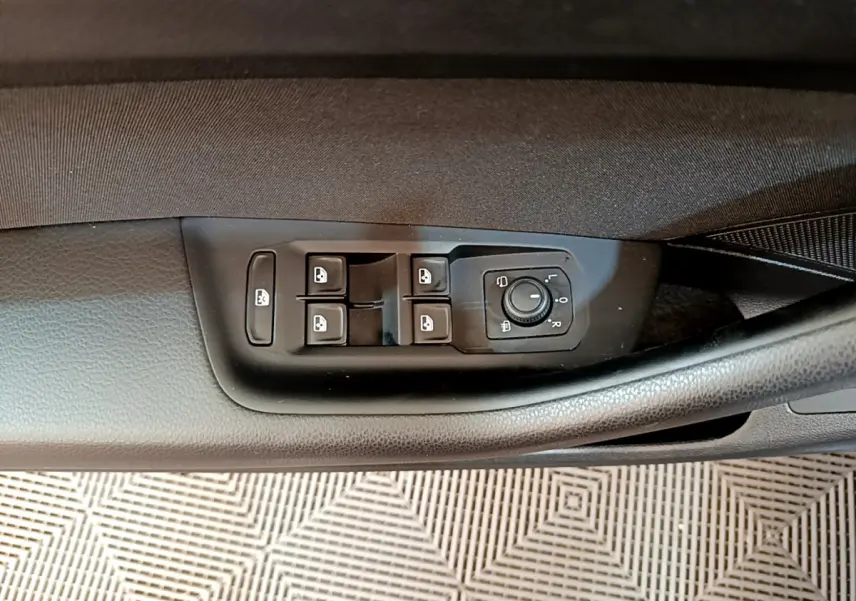 Commande des vitres et réglage des rétroviseurs côté conducteur sur la porte intérieure d'une Volkswagen Passat gris foncé.