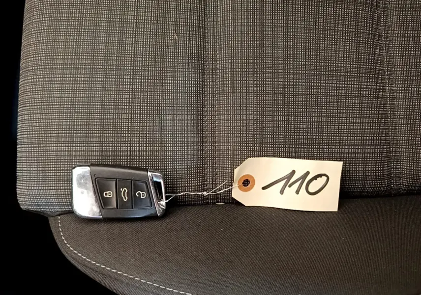 Clé de voiture Volkswagen Passat 2.0 TDI posée sur siège tissu gris à motif quadrillé avec étiquette 110.