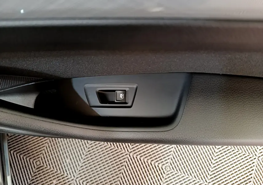 Gros plan sur la poignée intérieure de verrouillage de porte côté gauche d’une Volkswagen Passat gris foncé.