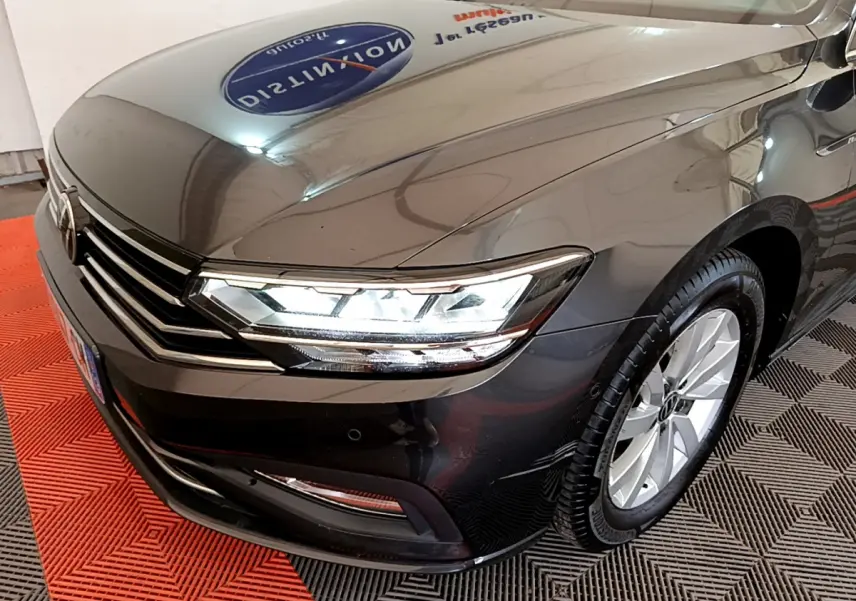 Vue 3/4 avant droit d'une Volkswagen Passat gris foncé avec phares LED allumés et jantes alliage visibles.