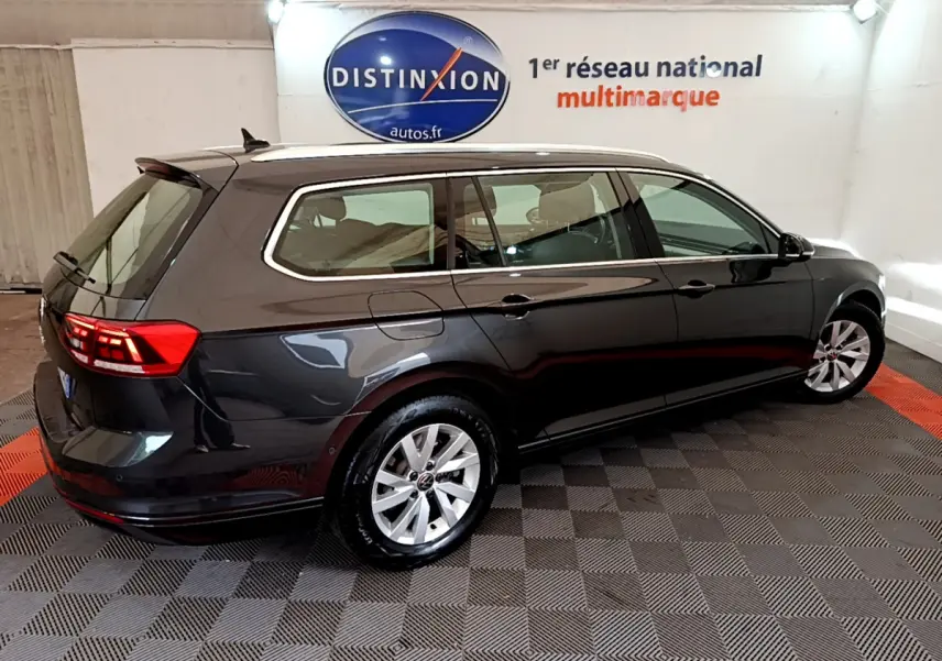 Volkswagen Passat break gris foncé vue 3/4 arrière droit en intérieur avec logo Distinxion en arrière-plan