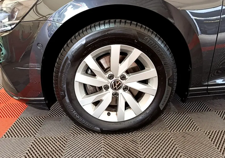Gros plan sur la roue avant gauche d'une Volkswagen Passat gris foncé, jante alliage et pneu Bridgestone visibles.