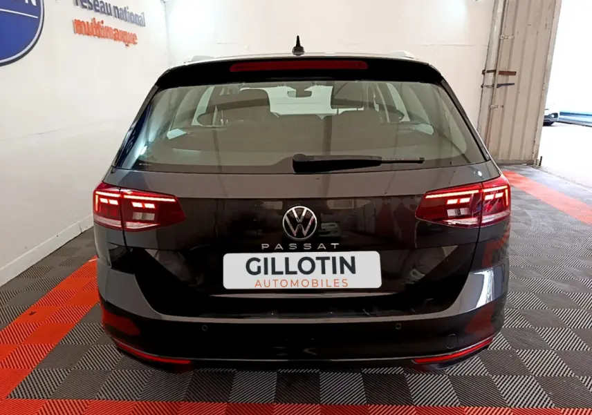 Vue arrière d'une Volkswagen Passat gris foncé avec feux LED allumés dans un garage.