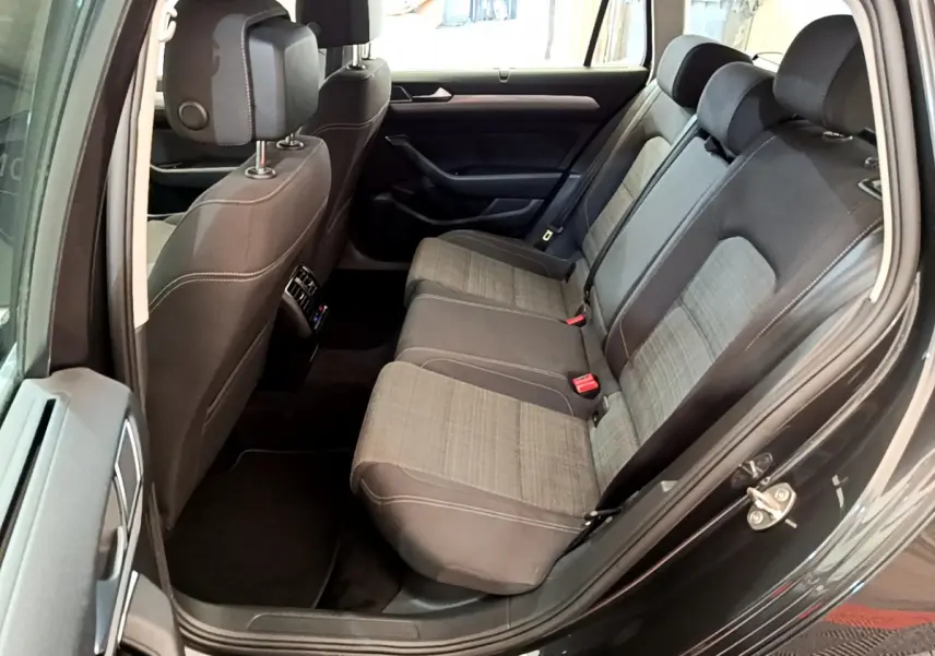 Vue côté gauche de l'habitacle arrière gris foncé de la Volkswagen Passat 2021 avec sièges tissu bicolore et appuie-têtes.