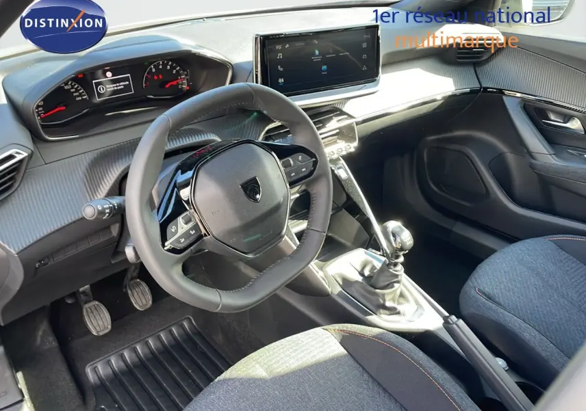 Intérieur du Peugeot 2008 2025 en tissu gris, vue côté conducteur montrant volant, tableau de bord et levier de vitesses manuel.