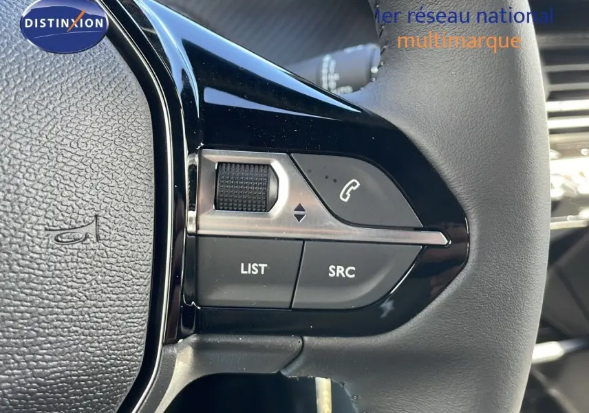Gros plan sur les commandes gauche du volant du Peugeot 2008 blanc Okenite Metal, avec boutons audio et téléphone intégrés.