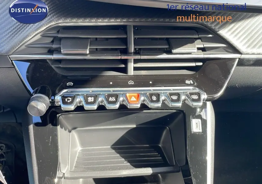 Vue rapprochée de la console centrale noire brillante du Peugeot 2008 blanc, mettant en valeur les commandes et aérateurs.