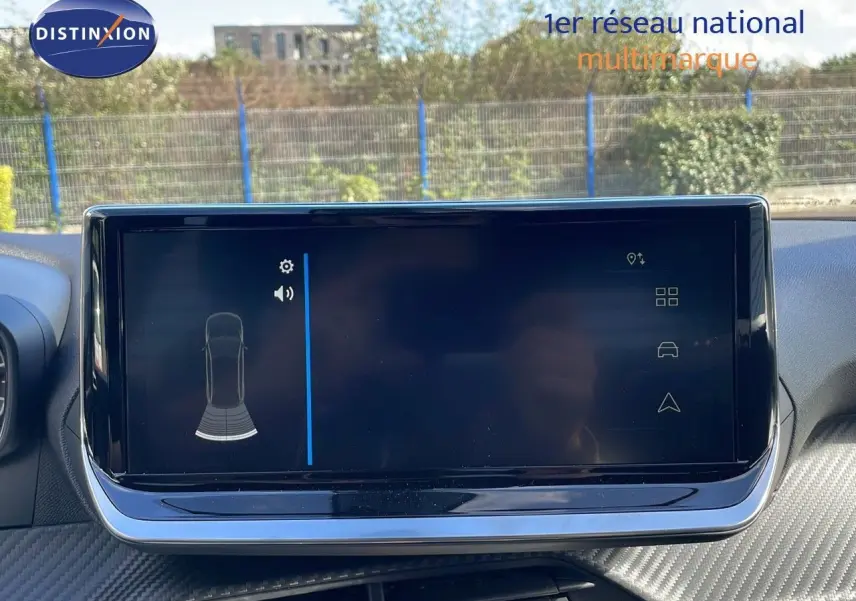 Écran tactile central du tableau de bord du Peugeot 2008 blanc, affichant les capteurs de stationnement arrière.