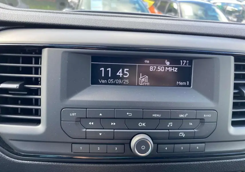 Tableau de bord du Peugeot Expert Fourgon gris Artense, affichant l'horloge et la radio FM à 87,5 MHz.