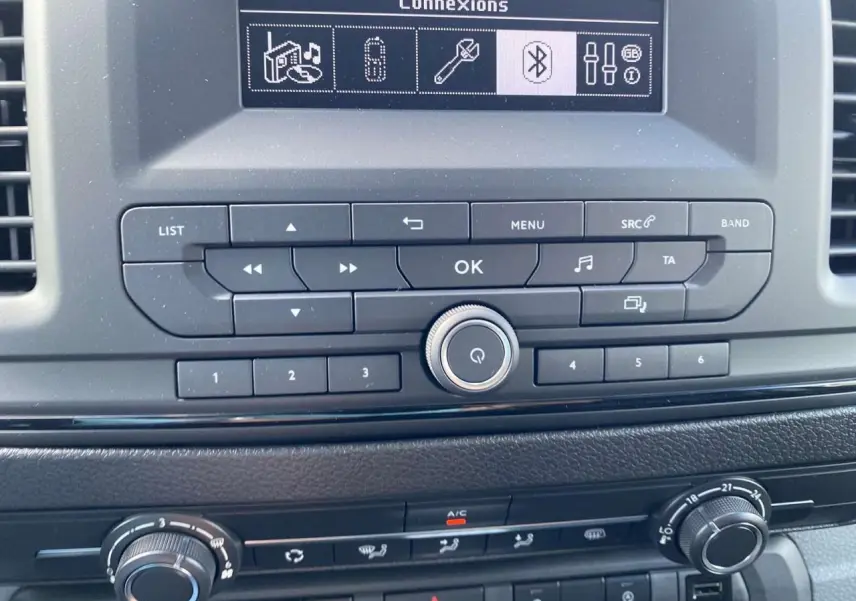 Tableau de bord du Peugeot Expert Fourgon gris Artense, vue centrée sur la console avec commandes audio et climatisation.