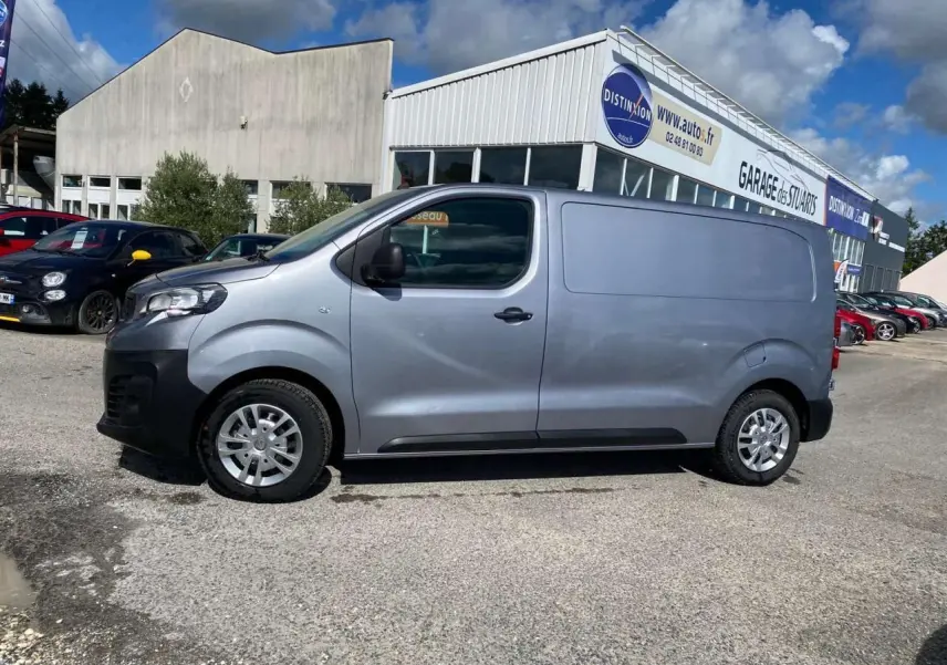 Peugeot Expert Fourgon gris Artense métal vu de profil côté gauche, stationné devant un garage.