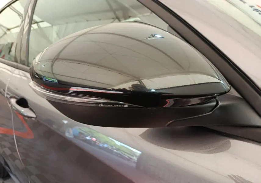 Rétroviseur droit noir brillant sur Alfa Romeo Stelvio gris foncé, vue rapprochée du côté passager.