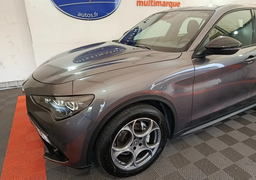 Vue 3/4 avant droit d'un Alfa Romeo Stelvio gris foncé avec jantes distinctives et phares LED ellipsoïdaux.