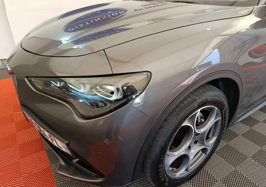 Gros plan sur l'avant droit gris foncé de l'Alfa Romeo Stelvio 2.2 TD 160 AT8 Sprint avec phares LED et jante distinctive.