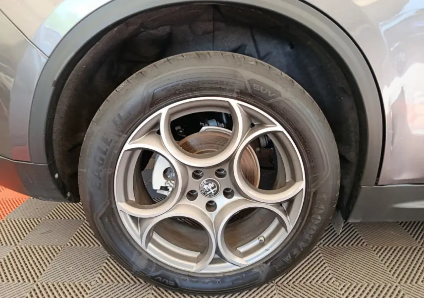 Gros plan sur la roue avant droite gris foncé d'un Alfa Romeo Stelvio 2.2 TD 160 AT8 Sprint avec jante distinctive à cinq cercles.