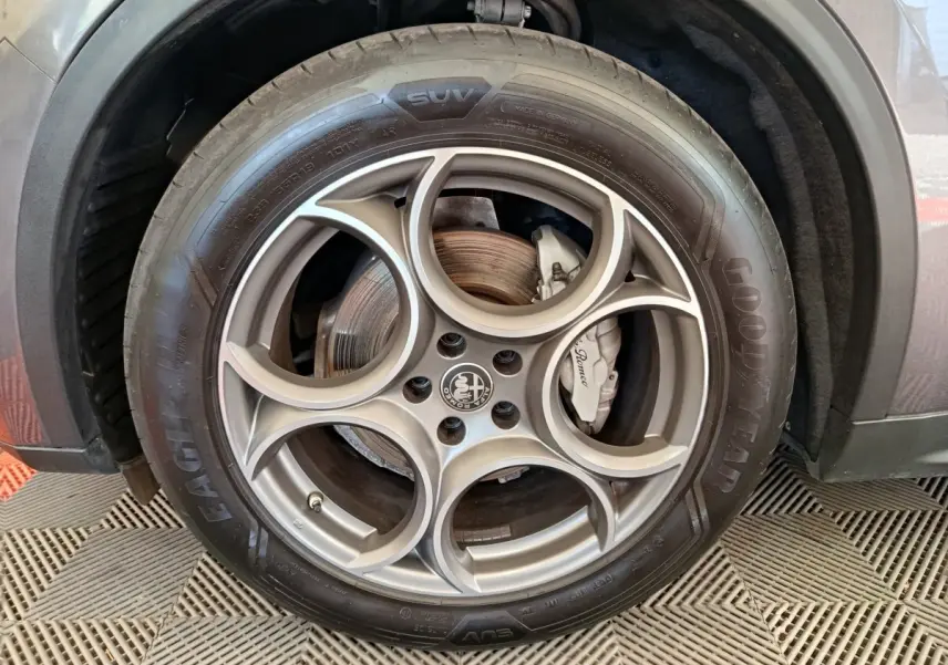 Gros plan sur la roue avant droite gris foncé d'Alfa Romeo Stelvio 2024 avec jante distinctive à cinq cercles.