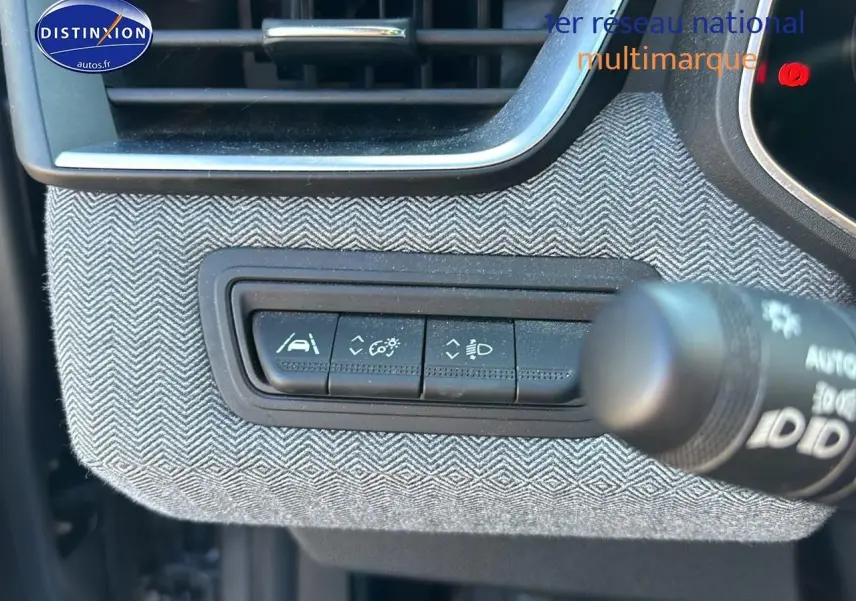 Gros plan sur les commandes d'assistance au conducteur avec habillage textile gris à motifs chevrons dans Renault Clio V gris Pizzara.