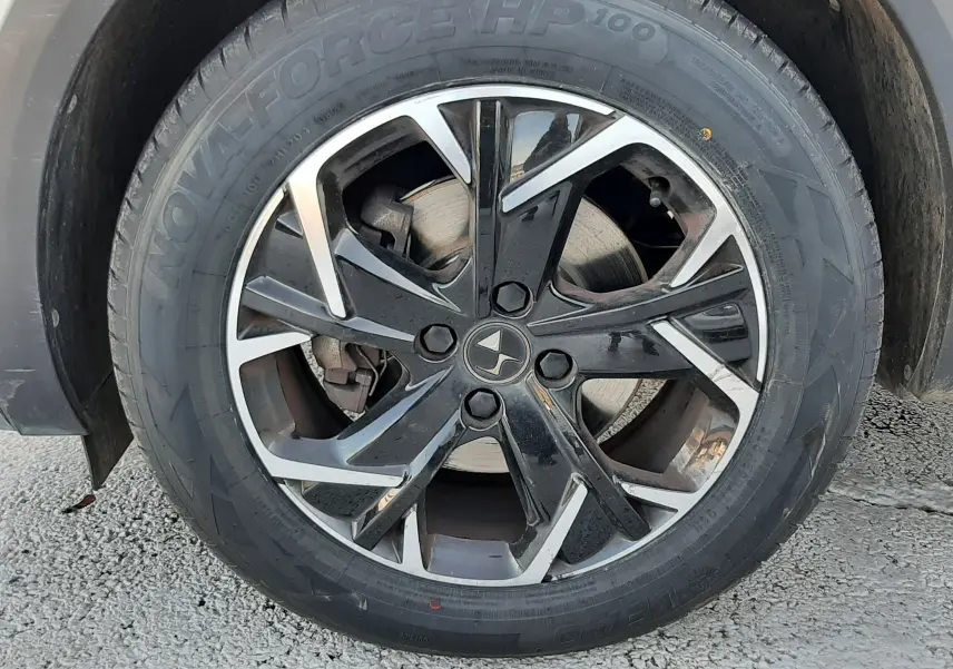 Gros plan sur la roue avant droite du DS3 Crossback blanc perle, jante alliage noir et argent avec logo DS central.