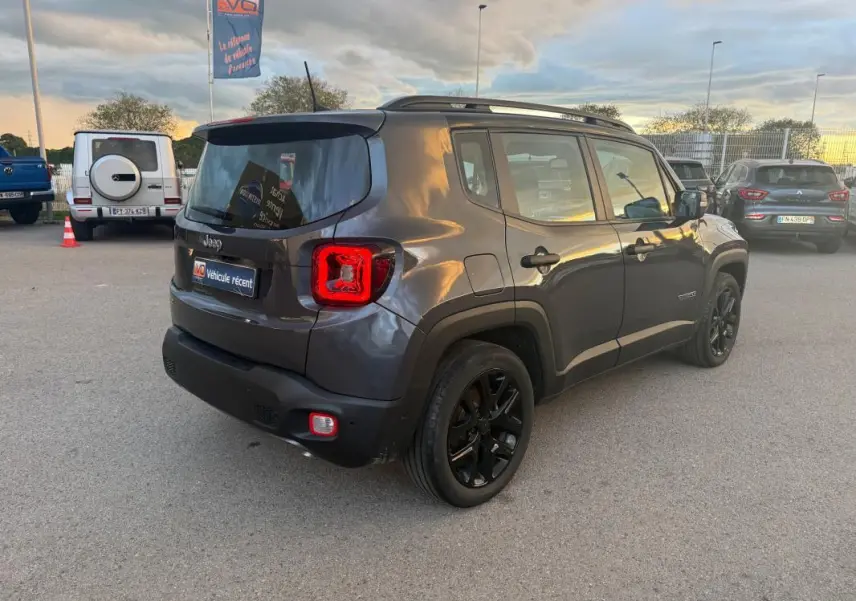 Jeep Renegade gris anthracite vue 3/4 arrière droit, avec barres de toit et jantes alliage noires 18 pouces.
