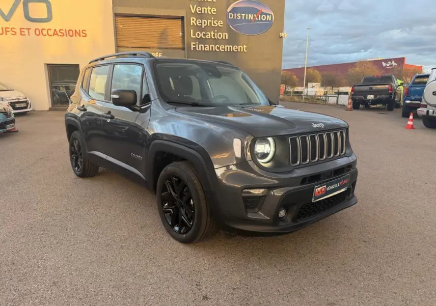 Jeep Renegade gris anthracite en 3/4 avant droit, avec jantes alliage noires et barres de toit visibles.