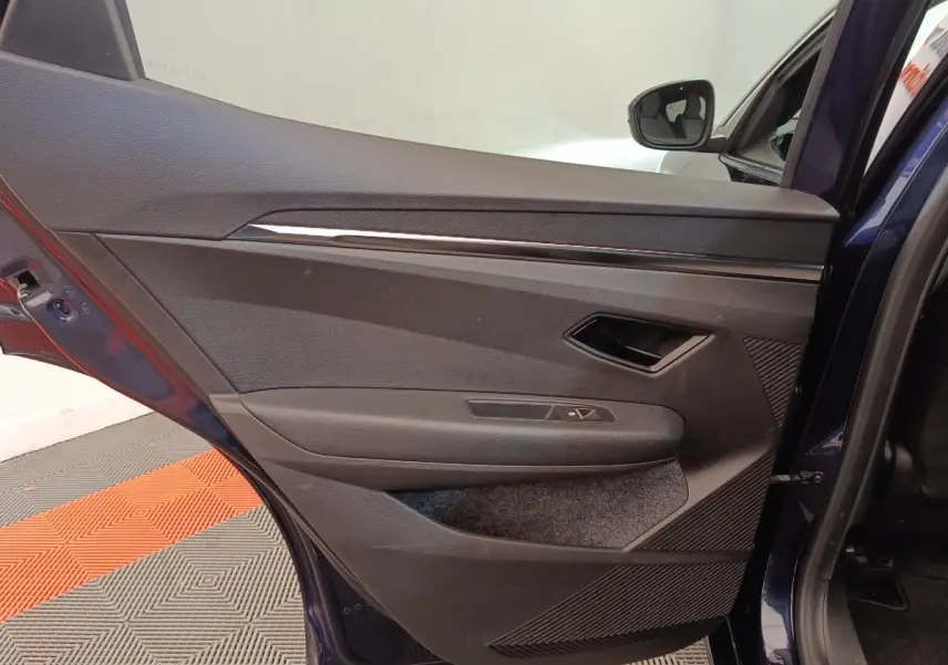 Vue intérieure de la porte arrière droite bleu foncé de la Renault Megane Techno EV60 avec garniture noire et commandes de fenêtre.
