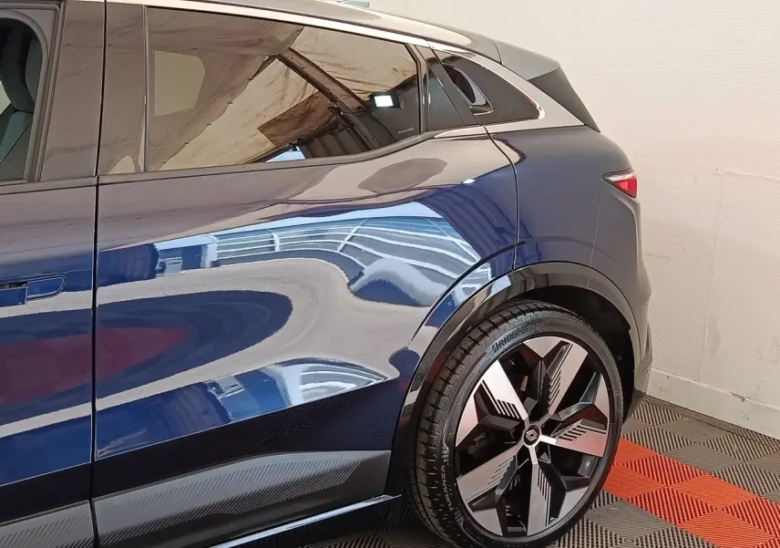 Vue latérale arrière droite d'une Renault Mégane Techno EV60 bleu électrique avec jante alliage distinctive.