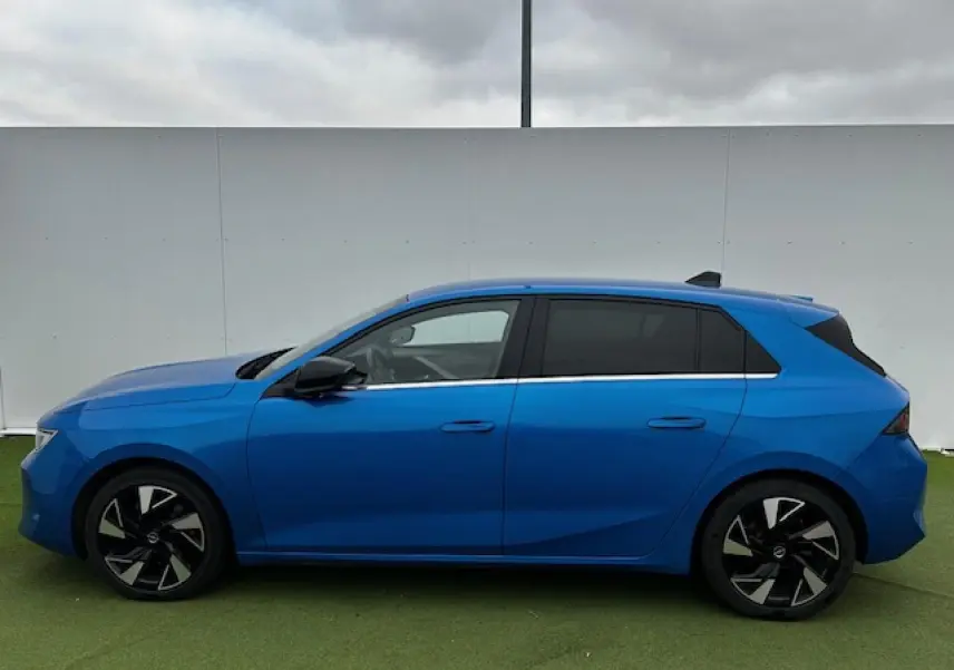 Profil latéral droit d'une Opel Astra VI bleu clair avec jantes alliage noires et vitres surteintées.