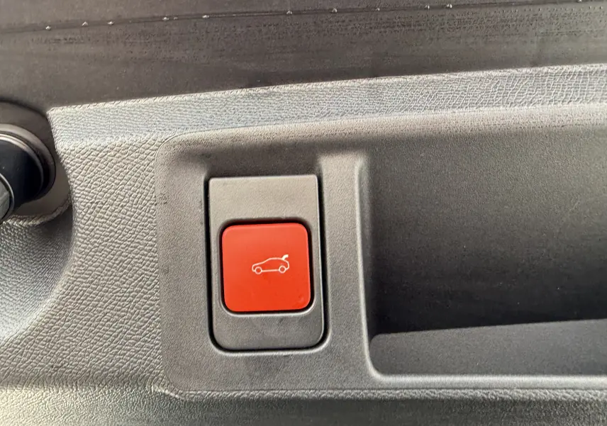 Bouton rouge d'ouverture électrique du hayon sur le panneau intérieur d'une Peugeot 308 SW 2024 bleu Avatar.