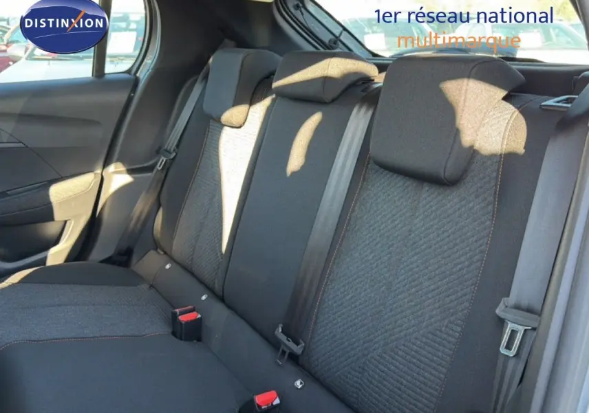 Vue intérieure sur les sièges arrière en tissu gris et noir de la Peugeot 208 hybride 2025, avec ceintures et appuie-têtes visibles.