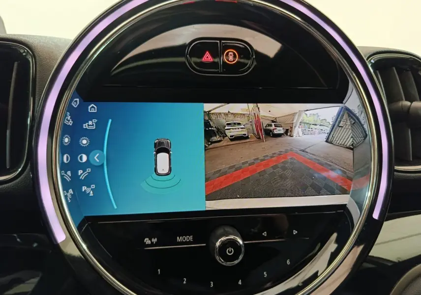 Écran tactile rond affichant la caméra de recul et les capteurs de stationnement du MINI Countryman blanc.