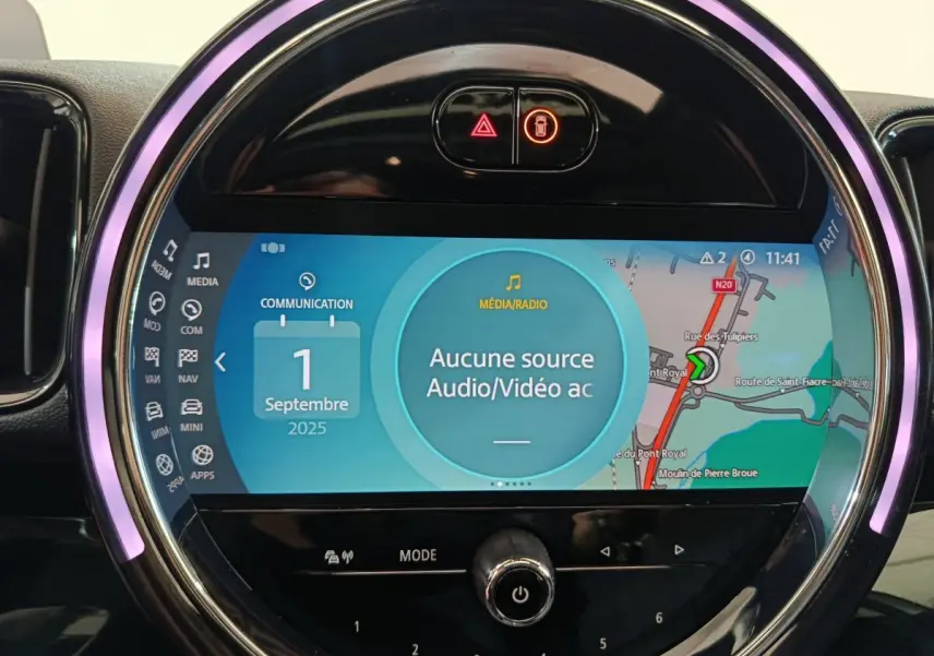 Gros plan sur l'écran tactile circulaire du tableau de bord de la MINI Countryman blanc, affichant la navigation et médias.