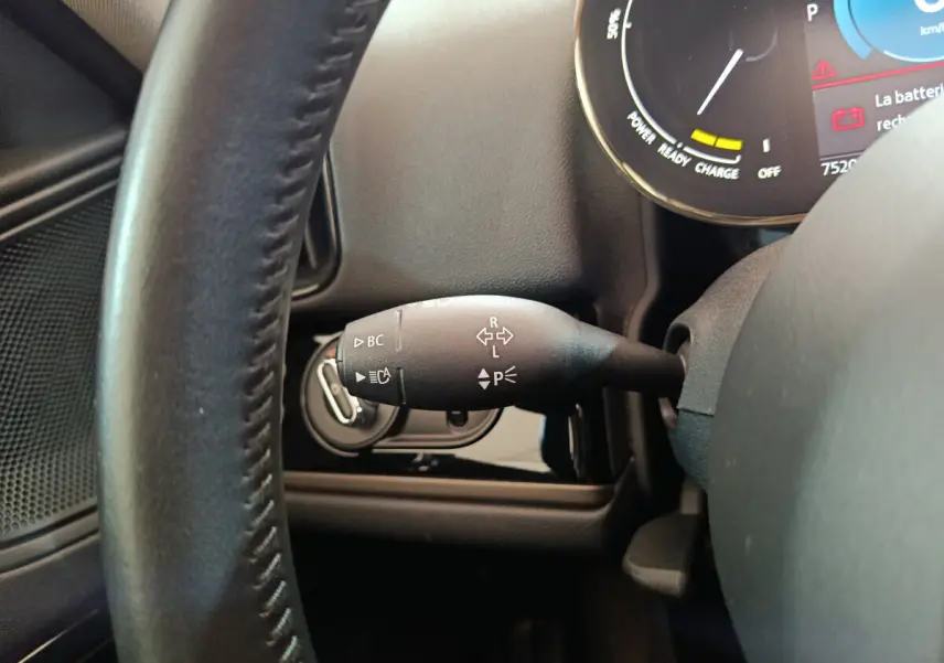 Gros plan sur le commodo gauche du volant cuir noir d'un MINI Countryman blanc, avec tableau de bord digital en arrière-plan.