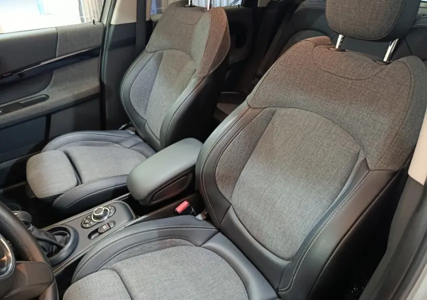 Vue rapprochée des sièges avant gris tissu et cuir du MINI COUNTRYMAN Cooper SE 2021, avec accoudoir central.