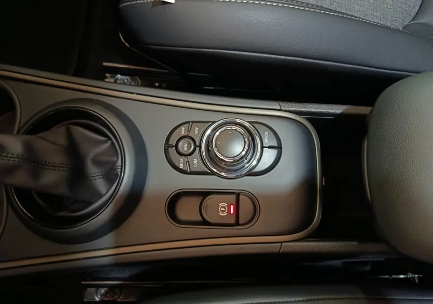 Vue rapprochée de la console centrale noire du MINI COUNTRYMAN Cooper SE avec molette de commande et frein à main électrique.