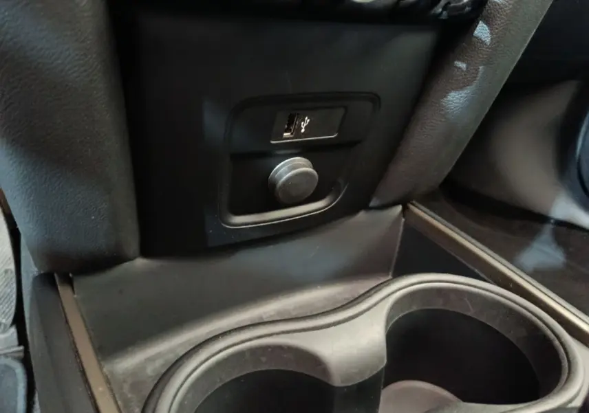 Prise USB et allume-cigare noirs en gros plan dans l’espace entre les sièges avant du MINI Countryman blanc 2021.