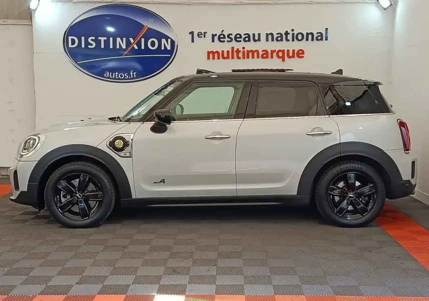Profil côté gauche d'une MINI Countryman Cooper SE hybride blanche avec toit noir et jantes noires brillantes.