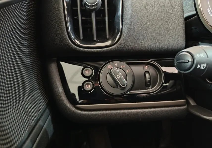 Gros plan sur la commande des phares noire brillante côté gauche du tableau de bord du MINI Countryman blanc 2021.