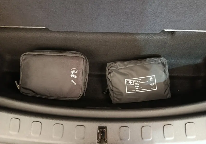 Vue plongeante sur le coffre du MINI Countryman blanc, montrant deux trousses de secours noires rangées.