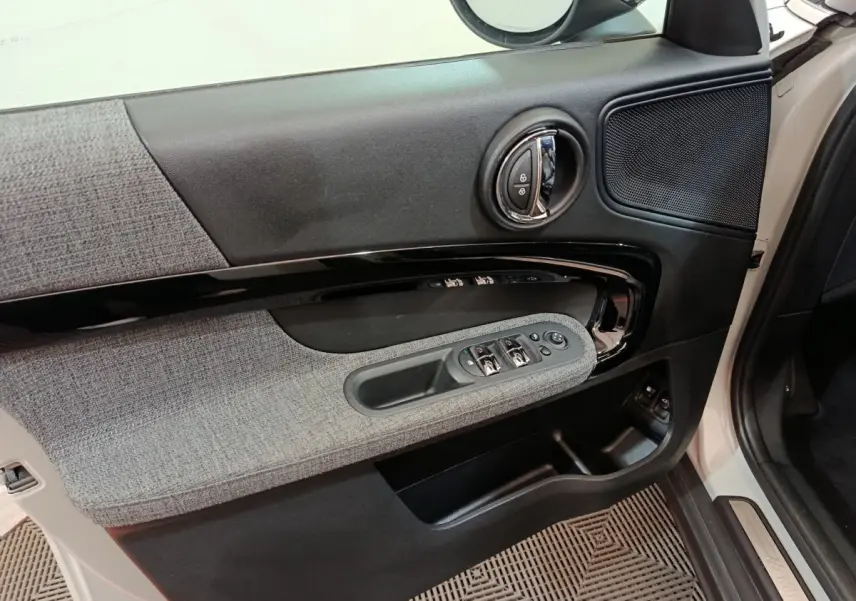 Intérieur côté gauche de la porte avant blanche du MINI Countryman 2021, avec garniture tissu gris et commandes électriques.