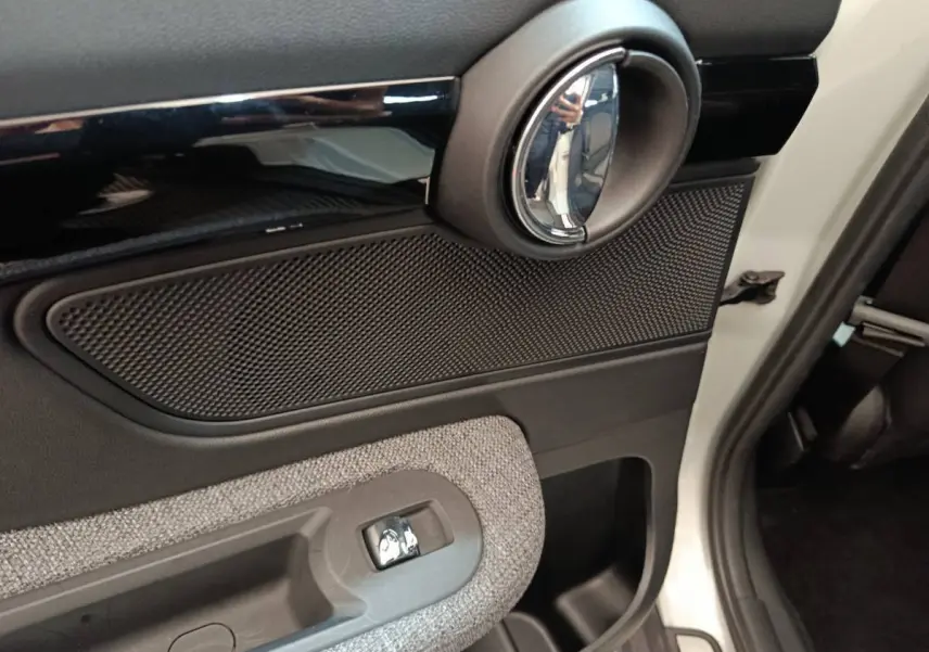 Détail de la porte côté droit blanche d'une MINI Countryman 2021 avec poignée chromée et habillage tissu gris.