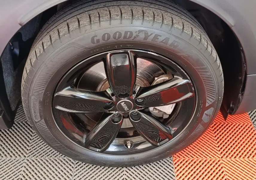 Gros plan sur la roue avant droite du MINI Countryman blanc avec jante noire brillante et pneu Goodyear.