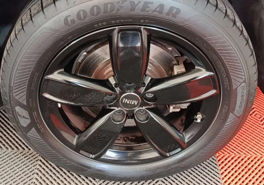 Gros plan sur la jante noire brillante de la MINI Countryman hybride, avec pneu Goodyear et logo MINI central.