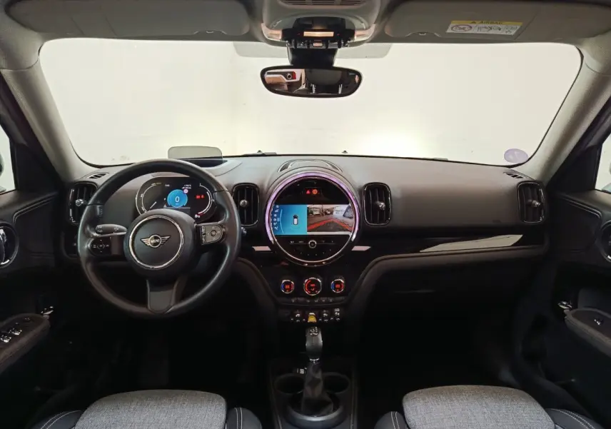 Intérieur noir et gris du MINI Countryman Cooper SE, vue frontale sur tableau de bord et écran tactile central rond.