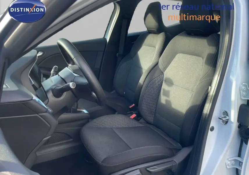 Intérieur de la Renault Clio blanc glacier vu côté conducteur, mettant en valeur les sièges tissu gris et le volant.