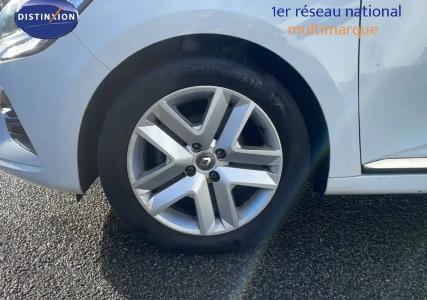 Gros plan sur la roue avant gauche de la Renault Clio blanche Glacier avec jante alliage et logo Renault central.