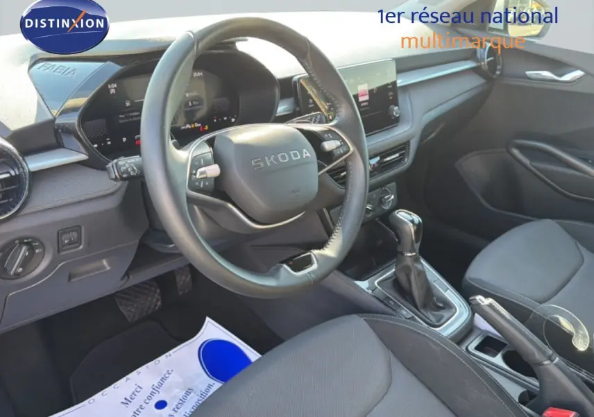 Vue intérieure côté conducteur du tableau de bord et volant noir de la Skoda Fabia 2025 avec boîte automatique et sellerie tissu.