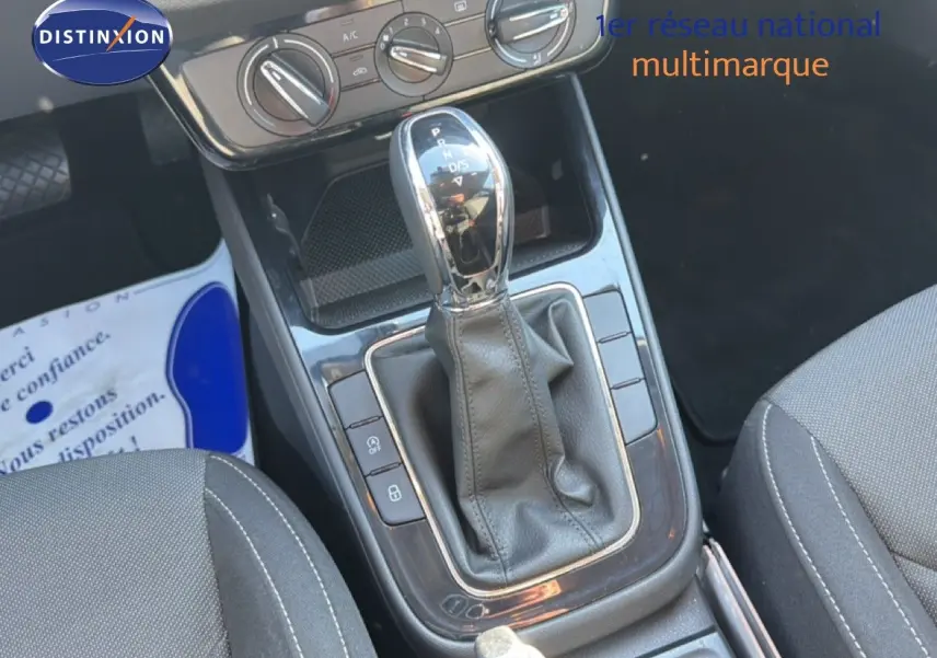 Gros plan sur la console centrale avec levier de vitesse automatique et commandes de climatisation d'une Skoda Fabia blanche.